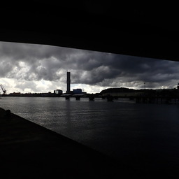 the Göta river under stormy clouds, framed by Hisingsbron above and the riverside footpath below