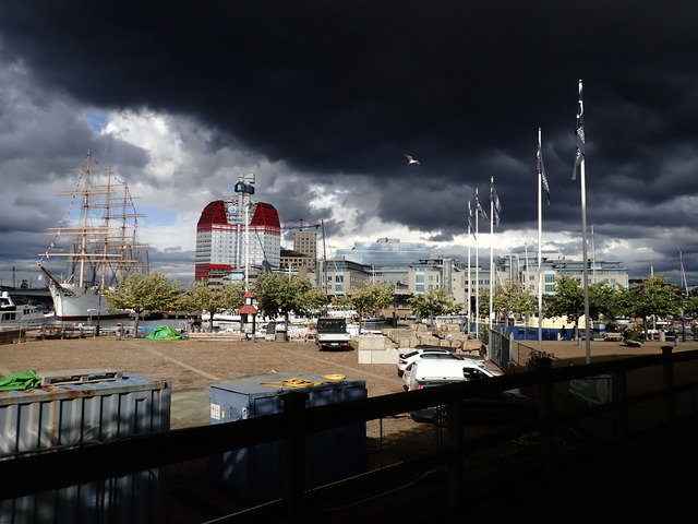 messy cityscape under a dramatic black sky with a white seagull against it; various landmarks are visible in the background but the foreground is some kind of construction site