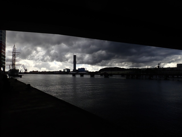 the Göta river under stormy clouds, framed by Hisingsbron above and the riverside footpath below